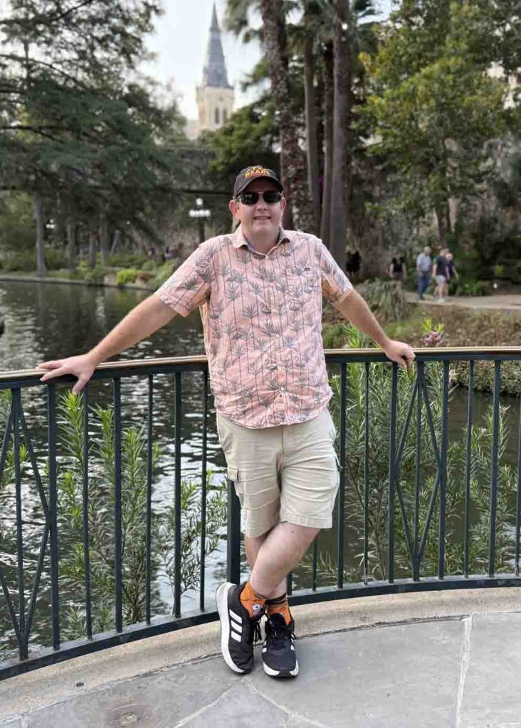 Matthew Mason beside a canal in a leafy park.