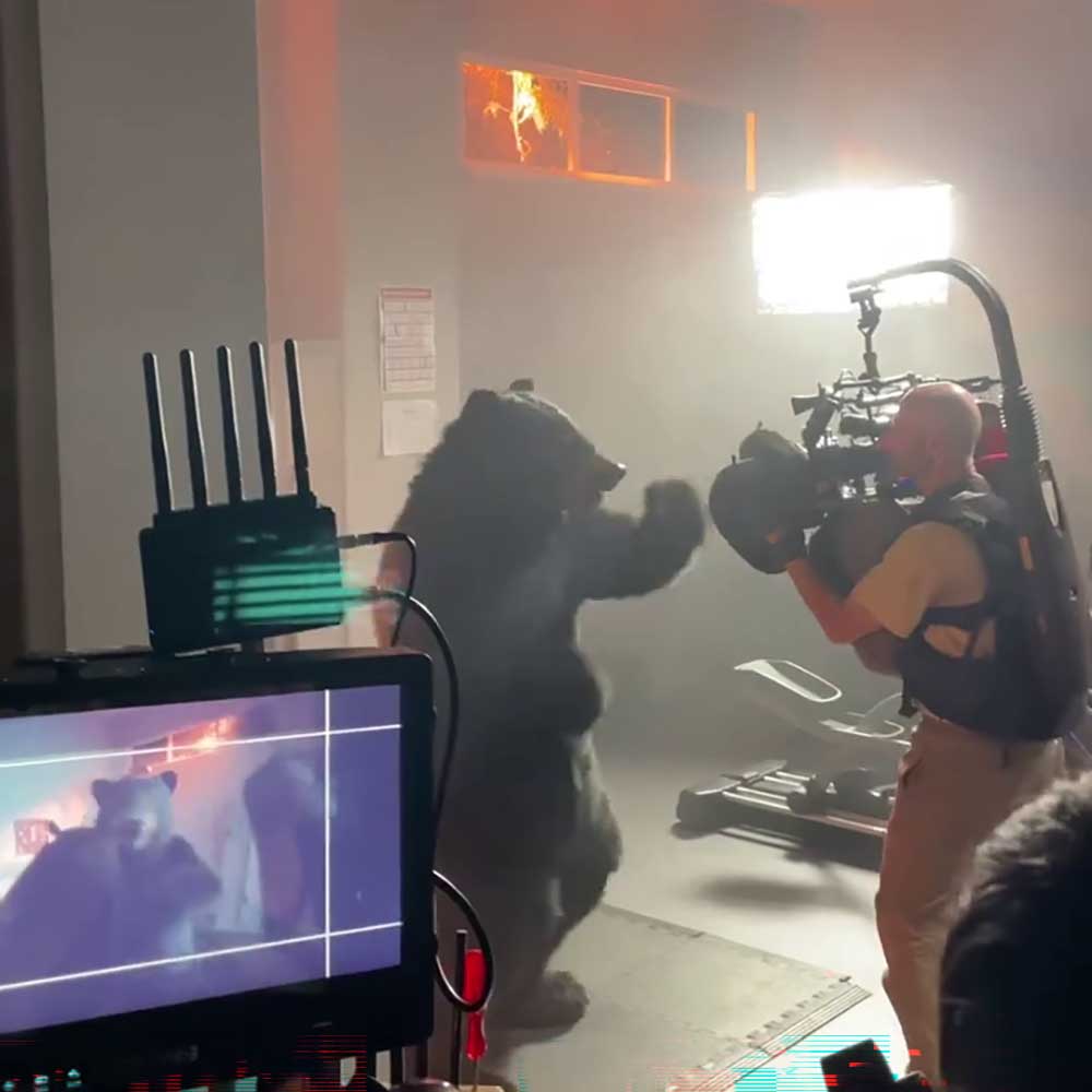 Bear actor Matthew Mason in a realistic bear suit facing a camera operator on the Nike Air Max DN set.